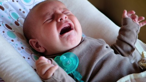 Newborn baby crying close-up. Mom tries to calm him down with a nipple