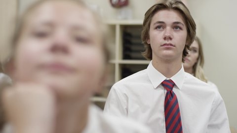 Secondary school students listen in class, depressed struggling boy looks sad