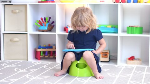 Toddler girl clapping hands sitting on the potty. Child on the potty. Potty training. 