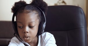 Webcam portrait of mixed race african american child emotional girl wearing headphones talking chatting online. Distant remote education. Little kid pupil blogger studying showing thumb up, likes sign