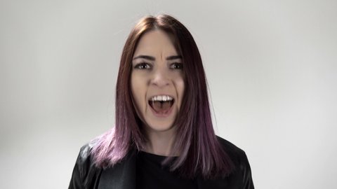 Portrait of young angry woman who is screaming on the white background. Caucasian stressed lady is shouting. There is a furious yelling female. Concept of person's negative emotions and mental health.