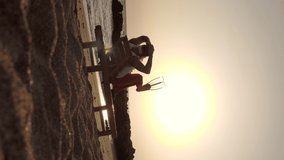 vertical video. Santa Claus summer vacation. Santa Claus sunbathes. back view. Funny Santa, in flippers, is sitting on lounger, on beach by the sea and enjoying the sunset or sunrise, relaxing. 