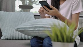 Asian woman using smartphone in living room.