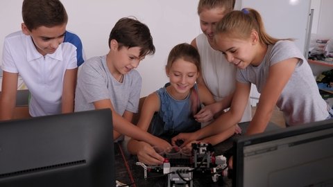 School children teenagers in robotics school makes robot managed from the constructor, robot programming.