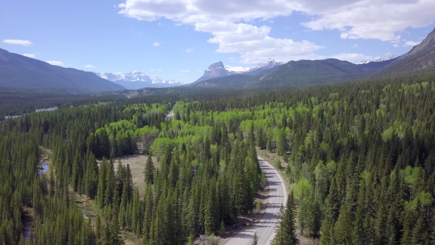 A motorcyclist drives along stunning black spruce forrest area in banff national park in Canada, aerial static shot