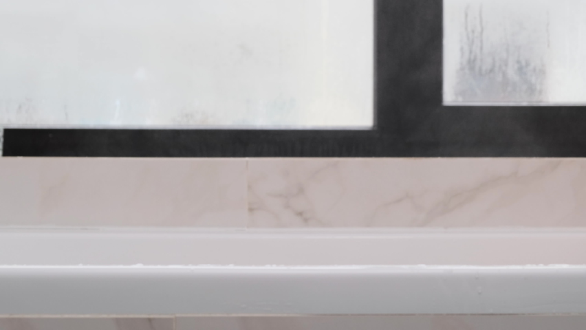 Side view of the bathroom. A beautiful blonde woman emerges from under the water. Relax concept. Steam comes from hot water