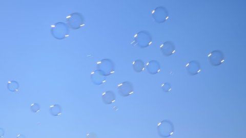 Blowing soap bubbles on blue sky background, outdoors