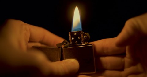 Man lights a flame and prepares to cook drugs. Drug abuser of opium or alkaloids. could also be used for torture or horror concepts. Light in the dark metaphor for religion.