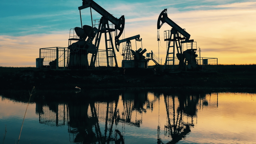 Sunset at the oil development site with a river nearby. Crude oil, gas, petroleum prices concept. Royalty-Free Stock Footage #1061770639