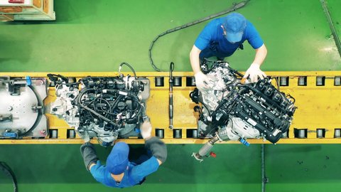 Workers assembling car engines at an industrial factory.