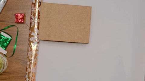 Step-by-step instructions for packing a gift for new year and Christmas. Shiny gold-colored paper with snowflakes. Step 1. Cut the wrapping paper with scissors.