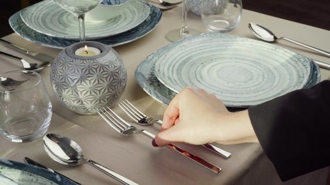 Close up of woman setting table. Hand of waitress or housewife putting silverware on dining table