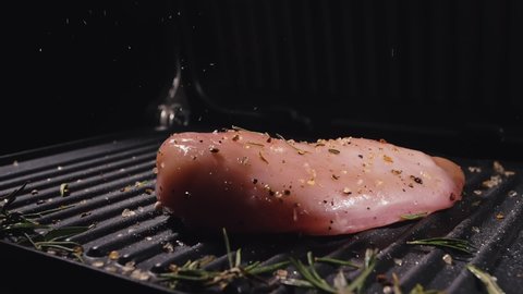 Delicious juicy meat steak toss on the grill. Cook grilling fresh chicken breast. Throw chicken fillet on electric roaster. Pour salt, rosemary, black pepper. Slow motion.