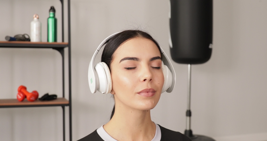 Sporty young woman listening to music while meditating in gym
