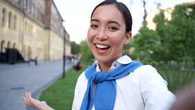 Cheerful asian woman talking to camera, having a video call outdoors. Point of view shot. Portrait.