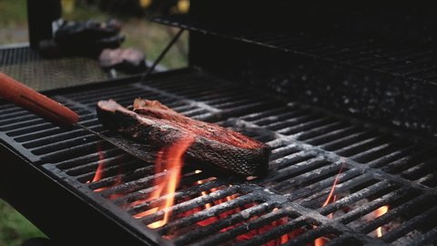 Salmon steak is grilled on the barbecue. Seafood on the grill. The cook puts a piece of smoked fish on the iron grill with a spatula to create a crispy crust. grilled seafood at picnic and bbq