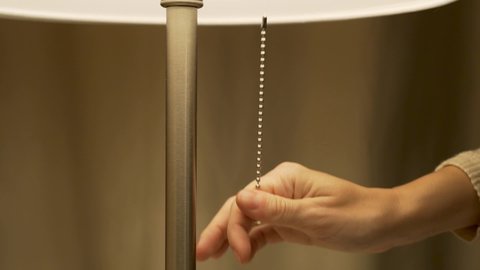 Close-up of a Female Hand, Including a Floor Lamp. Turning on the Floor Lamp in a Cozy Bedroom. Turning On The Lamp Light, Closeup.