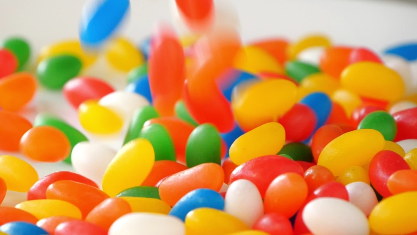 Multicolor Jelly Beans Candy Falls on White Background. Bright Tasty Colourful Texture Of Blue, Green, Yellow, Red, Orange and White Sweets in Motion Royalty-Free Stock Footage #1061786317