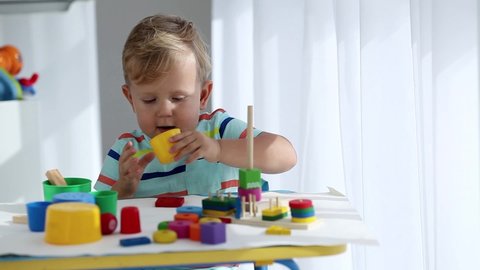 A little boy plays with wooden toys and dances. Educational logical toys for children. Montessori games for child development. Children's wooden toy.