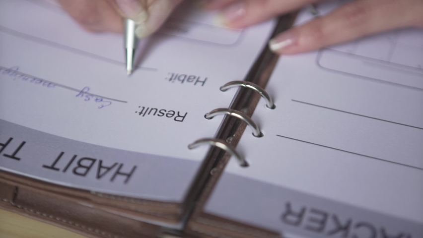 Close up shot of woman hands writing with silver pen in brown leather note book pad habit tracker bullet journal planner Royalty-Free Stock Footage #1061789956