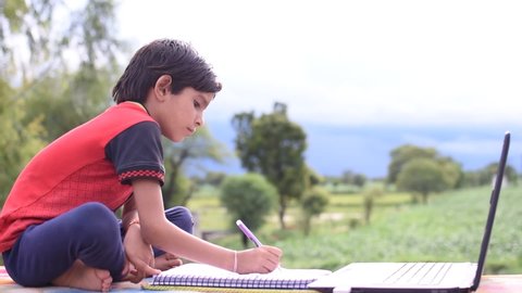 New Delhi, India. November 1,2020. Indian kid student doing self online study with laptop at home in outdoor with natural background.