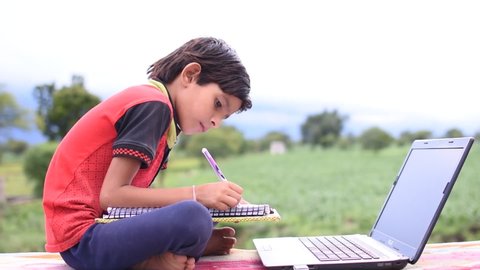 New Delhi, India. November 1,2020. Indian kid student doing self online study with laptop at home in outdoor with natural background.