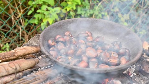 Chestnuts. Traditional Italian autumn delicacies cooked outdoors. Roasted chestnuts and maroni over the fire in a special steel pan. High quality FullHD footage . Soft focus