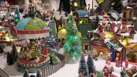 Christmas decor in  store window. Winter village in miniature. Christmas decor in store window. dynamic toy winter town, carousel, residents, snow, Santa Claus and trees. festive atmosphere