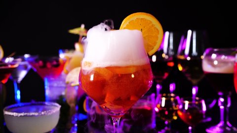 Aperol spritz drink with dry ice at bar counter close up. Bartender show and prepared cocktail with dry ice on a cocktail bar background. Colorful various drinks in a bar with dry ice smoke effect.