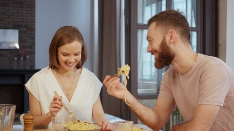 Young couple having dinner eating pasta at home