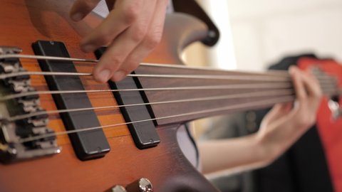 Close up of a professional bass guitar player, playing finger style on a fretless bass during a recording session. Shot in 4K.