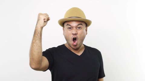 Guy put on hat in casual clothes surprised and shocked, looking with wide eyes, excited by an offer or win on isolated white background. 4K Resolution.