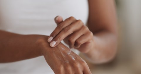 Female hands care. Close up shot of african american lady applying cream on hand skin, slow motion
