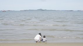 4K Video Mother and 3 years old asian kid playing on the beach. Background for family vacation and recreation.