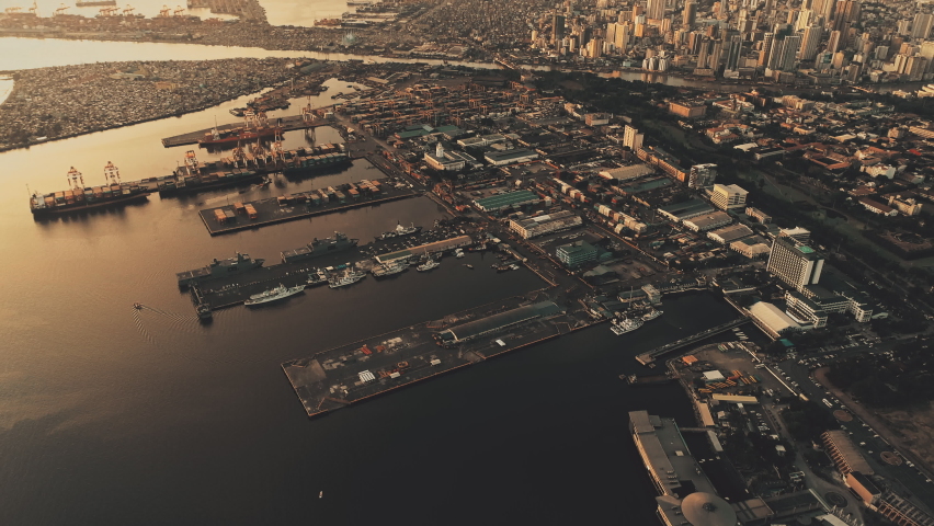 Sunset at metropolis port city at ocean bay aerial. Sun light at marina with ships, boats. Streets, roads at sunlight. Tropic cityscape of Manila capital town, Philippines. Epic nobody nature seascape