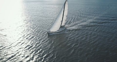 Sun reflection at closeup luxury yacht on ocean bay aerial. Wind white sails at passenger boat. Regatta race at open sea. Serene and calm seascape of Brodick Gulf, Arran Island, Scotland, Europe