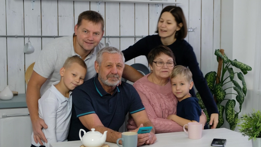 Happy big family woth grand parents and adul children, several generations in the kitchen smiling