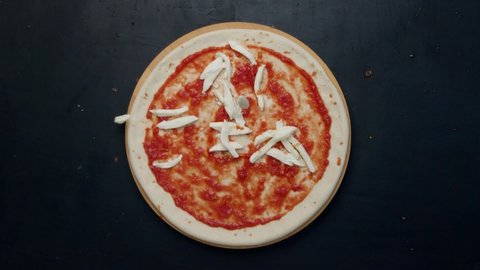 Сheese falls on the pizza. Cheese and pizza. Pizza production. Cheese tinder on dough.