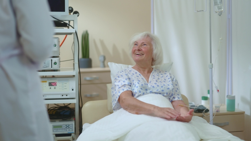 Beautiful old healthy looking lady lying in hospital bed having doctor appointment talking to her physician about diagnosis. Healthcare checkup. Medical concept. Communication. | Shutterstock HD Video #1061818924