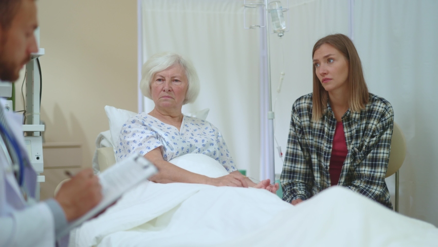 Caucasian family two women being told bad diagnosis frustrating feeling sad. Unhappy situation. Dreadful disease. Healthcare, family support. Hospital room. Doctor appointment. | Shutterstock HD Video #1061819158