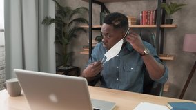 Young black man wearing protective face mask at office workplace. Remote chatting colleague internet online meeting conference webinar. Distance work webcam. Work during self-isolation and quarantine - Powered by Shutterstock - Get 15% off with code: PIKWIZARD15