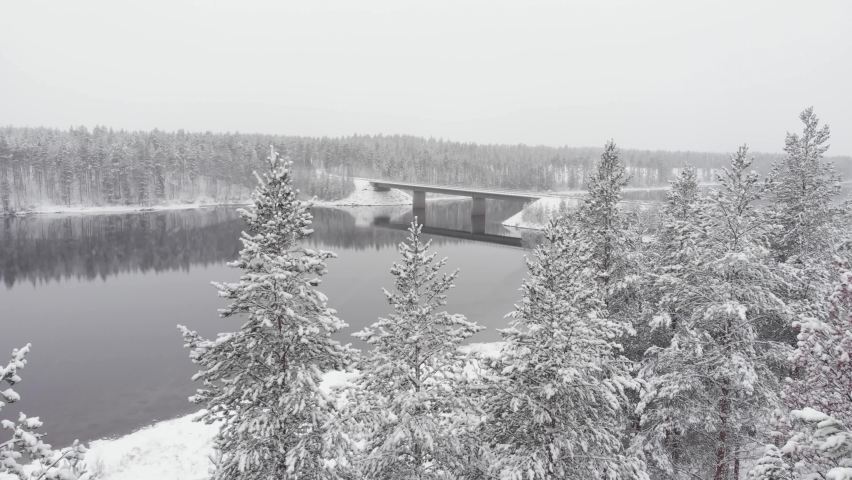 Frozen Bridge crossing the Vindel River near Snowy forest in Björksele, Västerbotten, Sweden. - Aerial point of interest