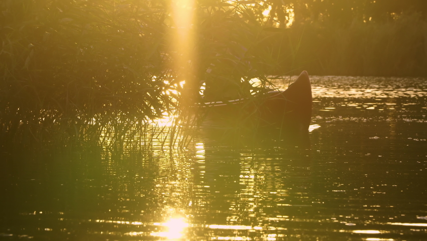A cowboy in a red canoe floats on the river in the forest. Beautiful sunlight at sunset. Wild west of America. 4K