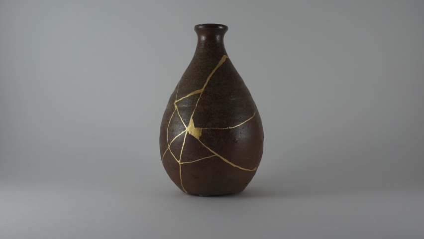 Kintsugi bottle with real gold cracks. Gold cracks lighted up.
Dark brown pottery. Trauma representation. Kintsugi, the Japanese art of restoring pottery with gold. | Shutterstock HD Video #1061831776