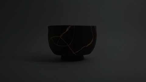 Kintsugi bowl with real gold cracks. Gold cracks lighted up.
Dark brown pottery. Trauma representation. Kintsugi, the Japanese art of restoring pottery with gold.