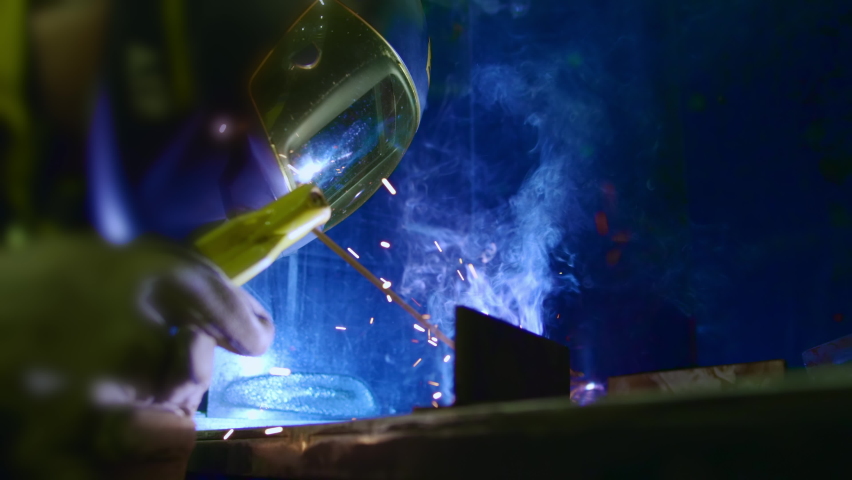 Factory worker welds metal. The man is welding. Welding with argon or electrode, using a welding machine. An industrial enterprise producing metal structures. Sparks and flashes fly. Slow motion Royalty-Free Stock Footage #1061832763