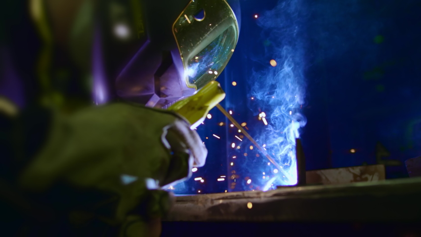 Factory worker welds metal. The man is welding. Welding with argon or electrode, using a welding machine. An industrial enterprise producing metal structures. Sparks and flashes fly. Slow motion Royalty-Free Stock Footage #1061832763