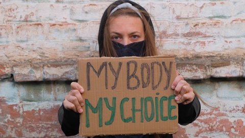 Young woman protester holds cardboard with MY BODY MY CHOICE sign. Girl protesting against anti-abortion laws. Feminist women power march. Feminism concept equal opportunity rights independence freedom