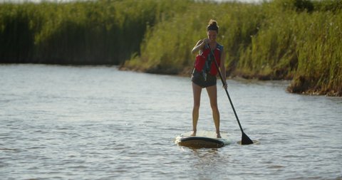 Happy young woman on a stand up paddleboard in the outer banks