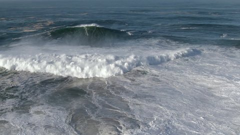 Aerial view of surfer riding giant wave in Nazare, Portugal. Nazare is famously known to surfers for having the biggest waves in the world.